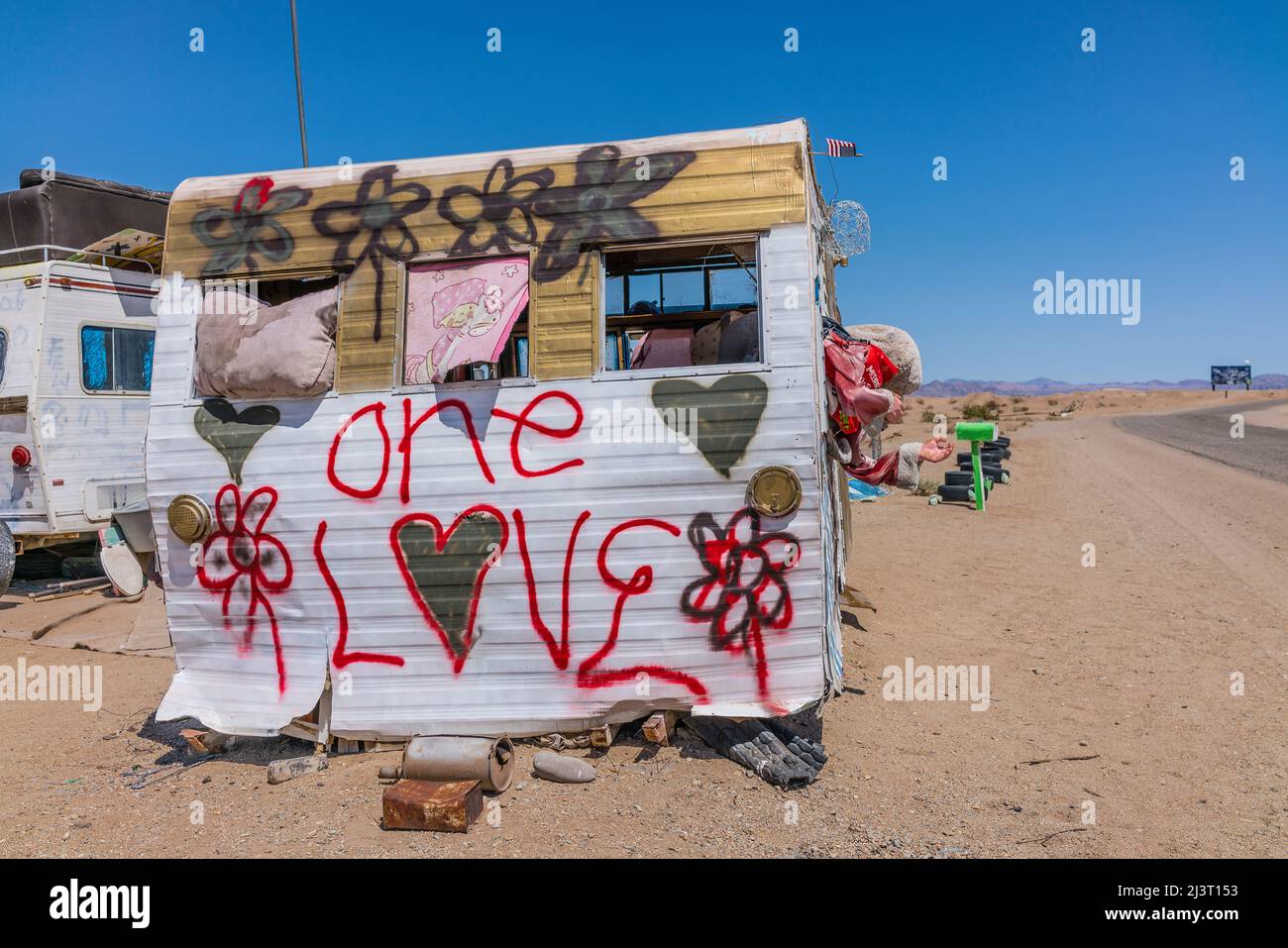 Sray painted trailer with 'one love' painted on the end in Slab City, California. Slab City, also called The Slabs, is an unincorporated, off-the-grid Stock Photo