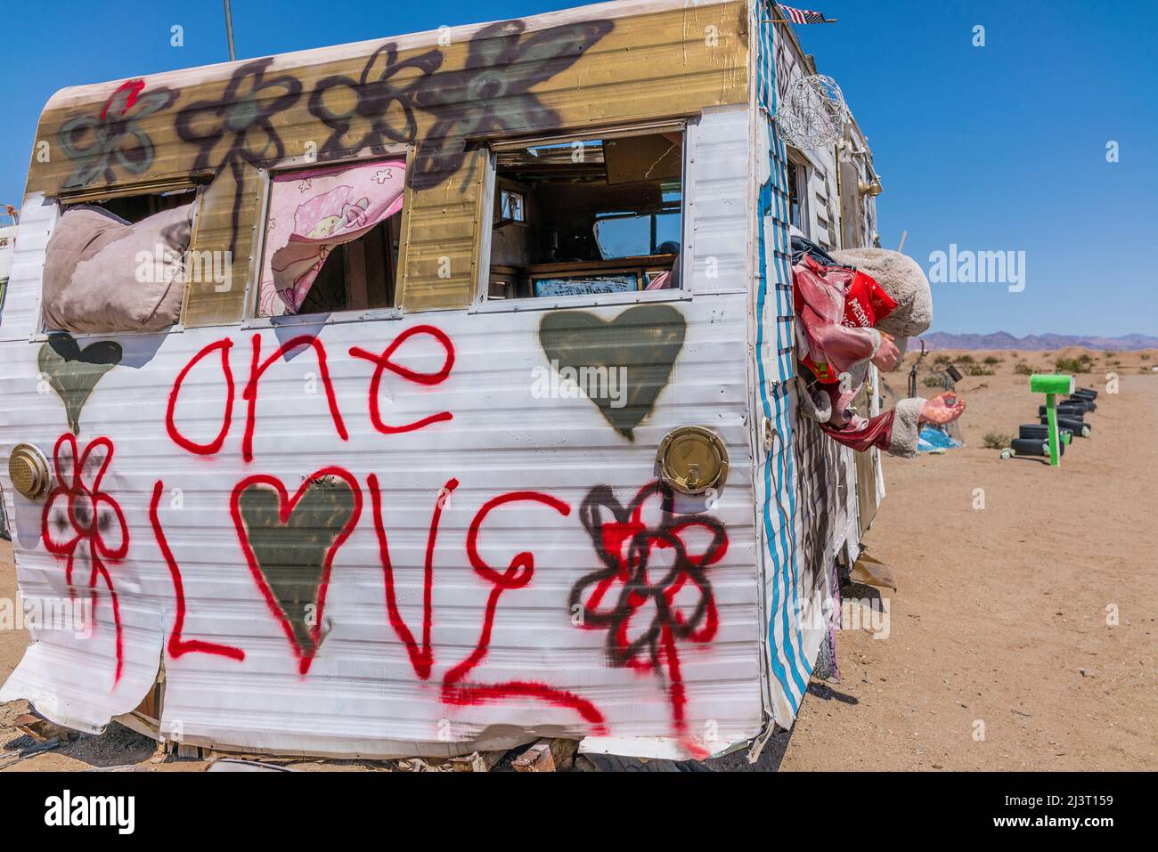 Sray painted trailer with 'one love' painted on the end in Slab City, California. Slab City, also called The Slabs, is an unincorporated, off-the-grid Stock Photo
