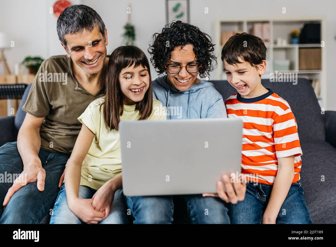Happy family using a laptop computer while sitting on a sofa together ...