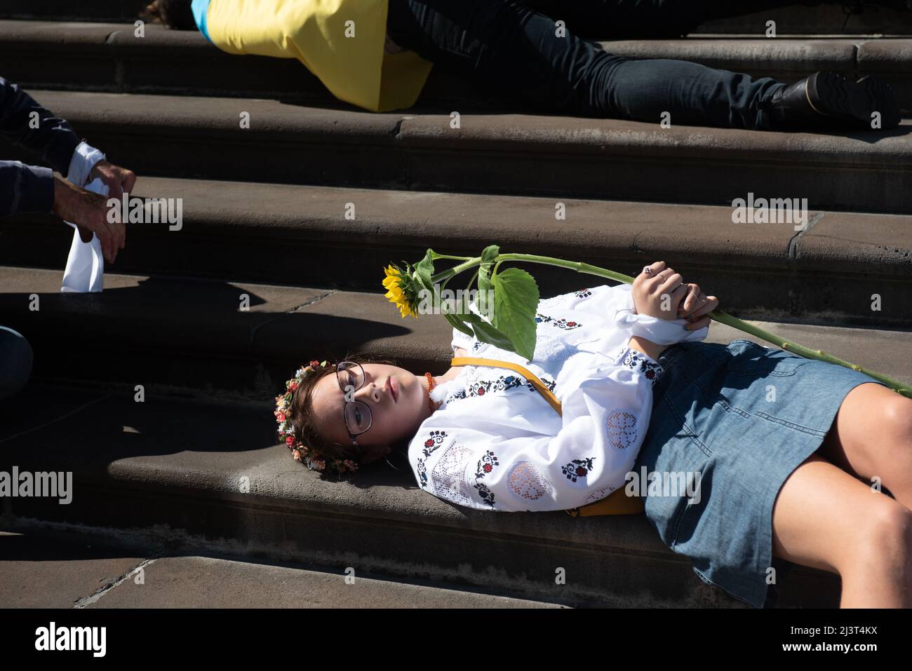 Melbourne, Australia. 10th Apr, 2022. A young girl lies on the steps of Parliament House in Melbourne, taking part in a demonstration in response to Russian troops killing Ukrainian civilians. Credit: Jay Kogler/Alamy Live News Stock Photo