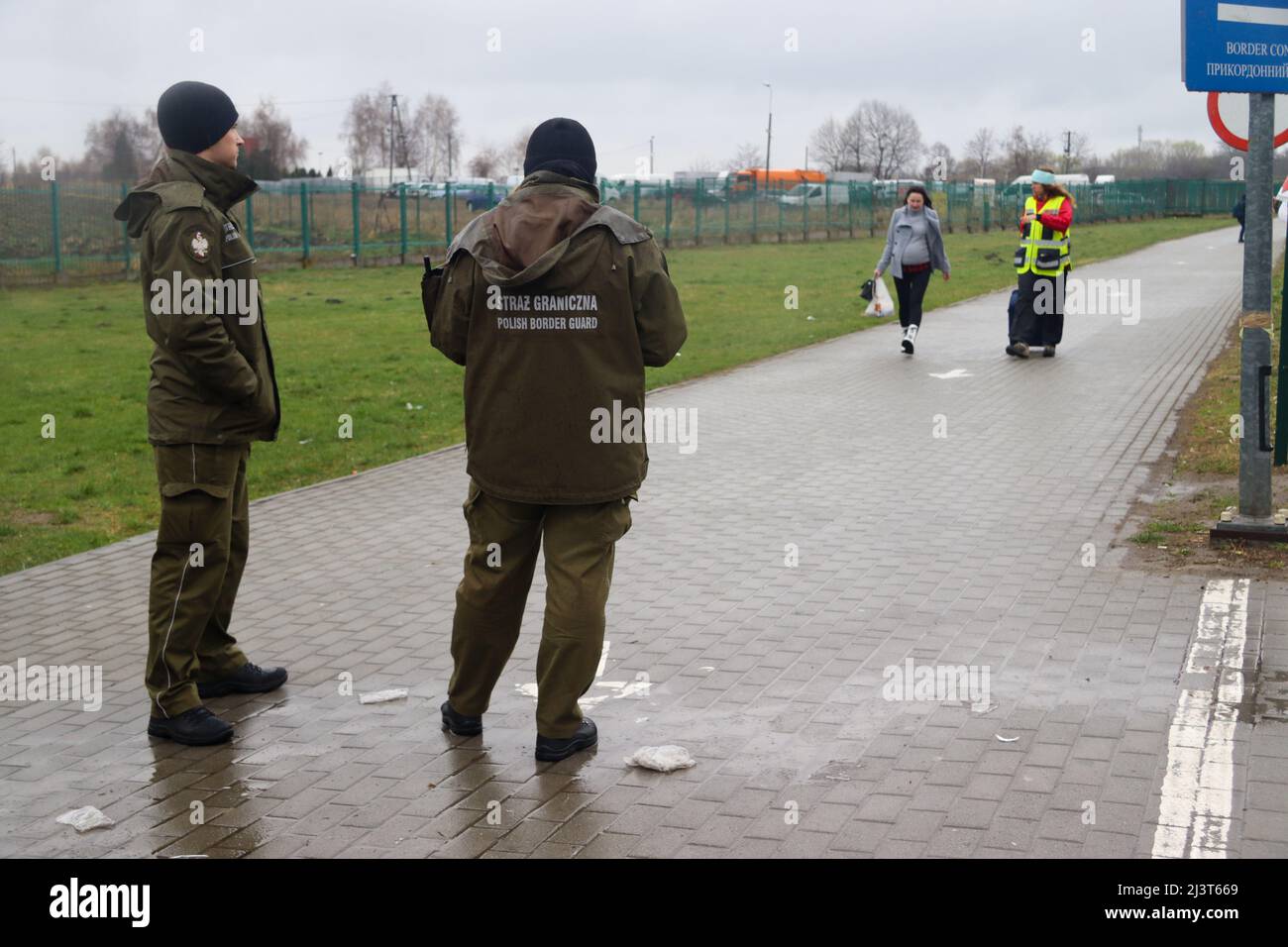 Medyka, Poland. 8th Apr, 2022. Polish Border Guards at the Polish/Ukraine border in background; they watch as a refugee makes her way to their gate, in Medyka (Credit Image: © Amy Katz/ZUMA Press Wire) Stock Photo