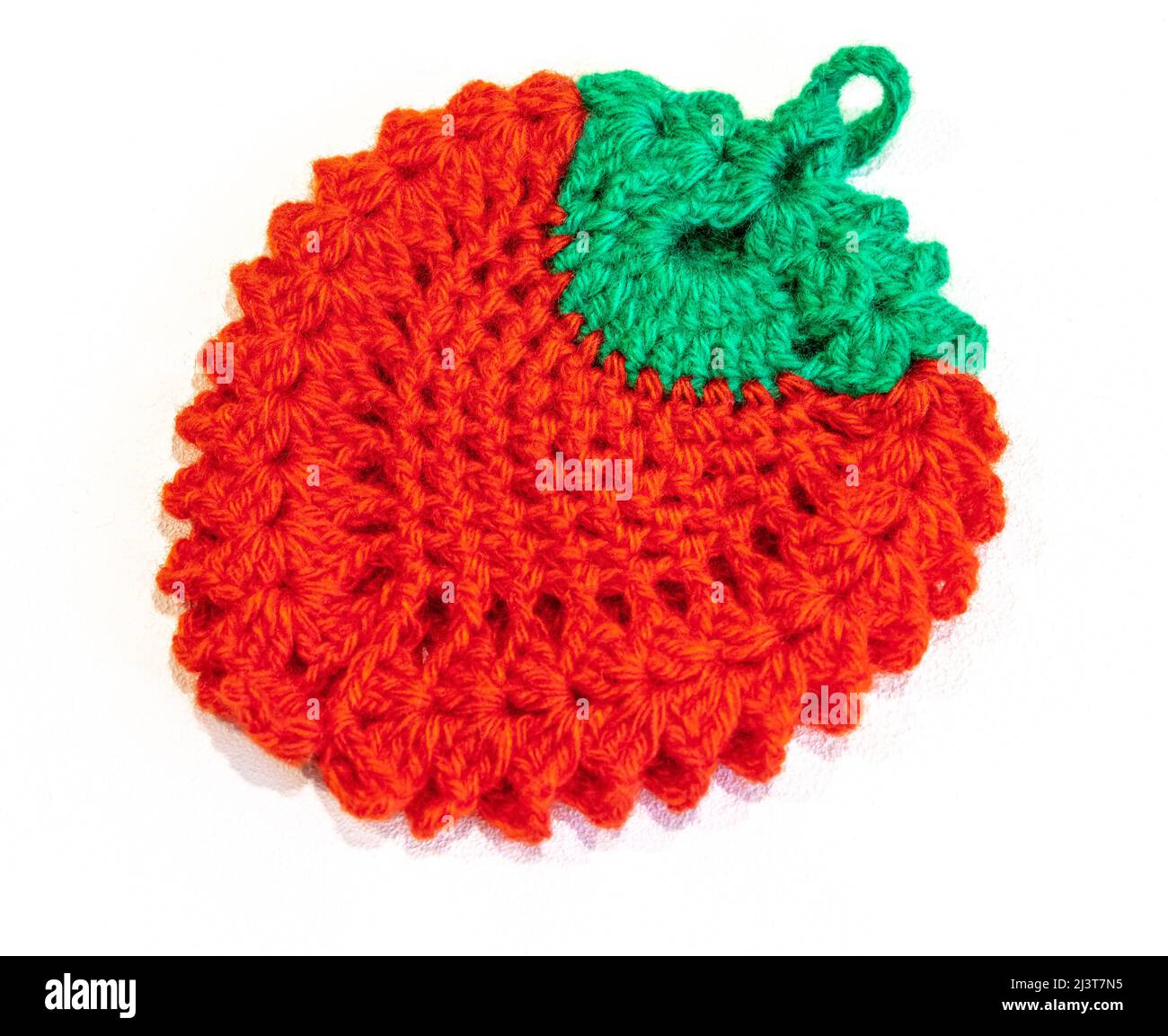 Knitted red-green rug in the form of a berry on a white background close-up. Stock Photo
