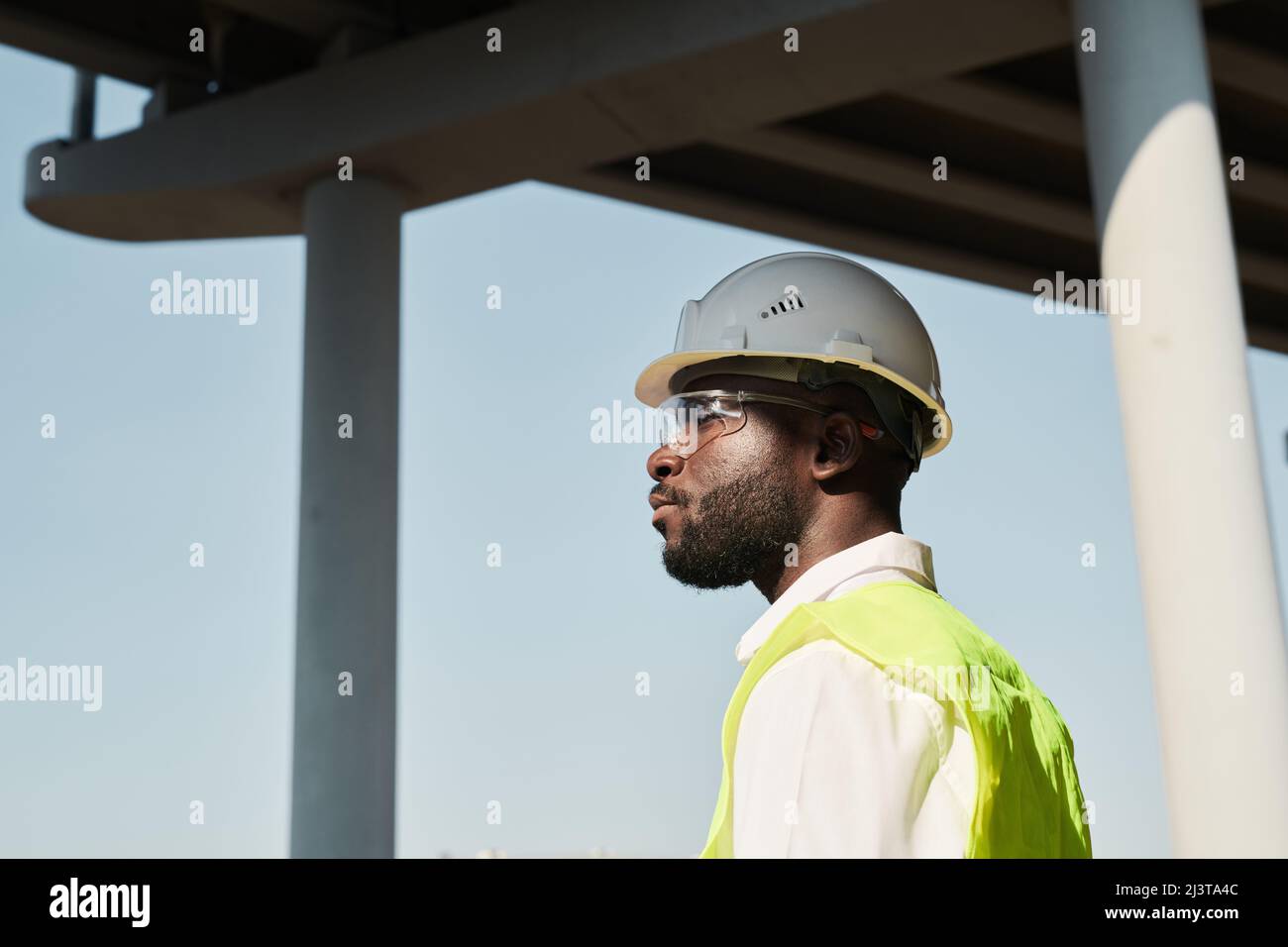 Professional engineer in hardhat in workwear standing at construction site Stock Photo