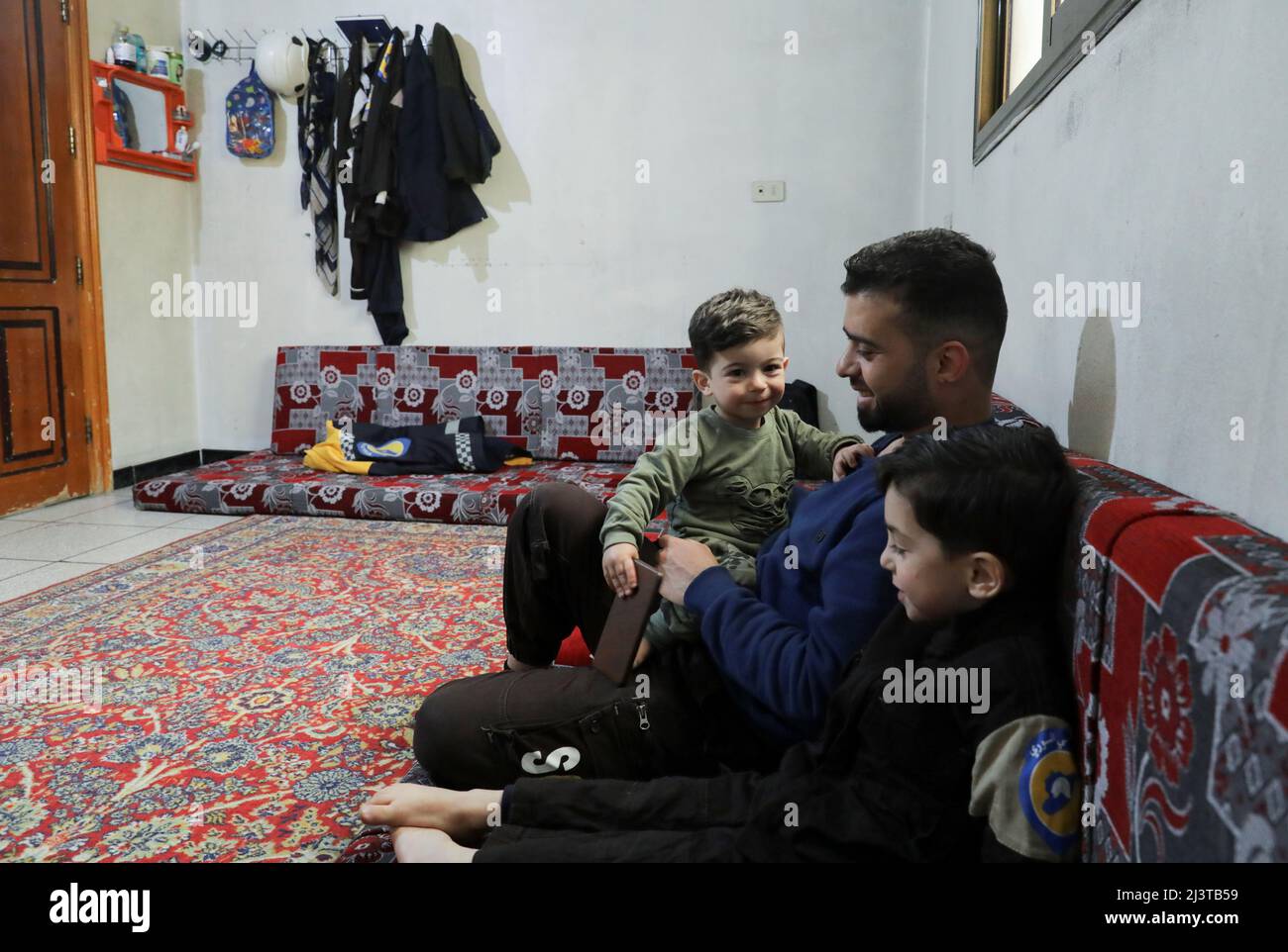 Hamid Ketteny, a civil defence rescue worker who says he carried the bodies of six children who were killed when poison gas was dropped in the town of Khan Sheikhoun in 2017, sits with his children at home in the rebel-held Idlib, Syria April 2, 2022. Picture taken April 2, 2022. REUTERS/Khalil Ashawi Stock Photo
