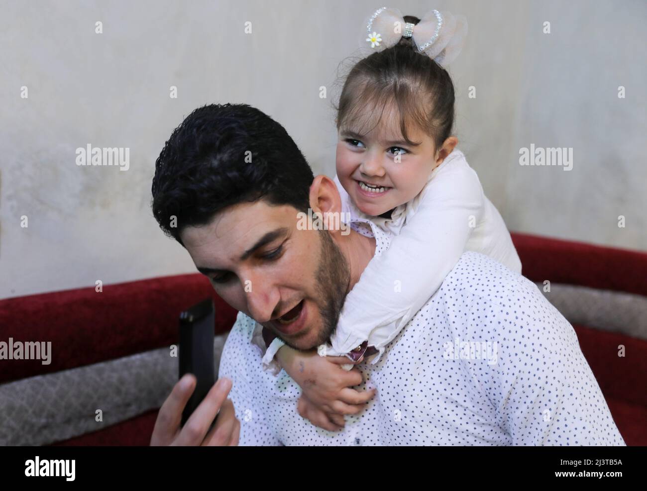 Abdel Hamid al-Youssef, an internally displaced man who says his wife and infant twins were killed when poison gas was dropped on their home town of Khan Sheikhoun in 2017, plays with his daughter, Aya, at their home in the rebel-held town of Sarmada in Idlib province, Syria April 1, 2022. Picture taken April 1, 2022. REUTERS/Khalil Ashawi Stock Photo