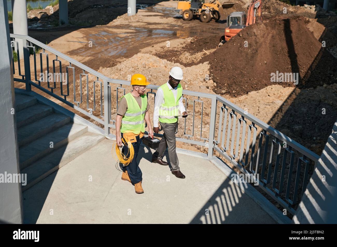 Two building contractors discussing project while standing at construction site, copy space Stock Photo