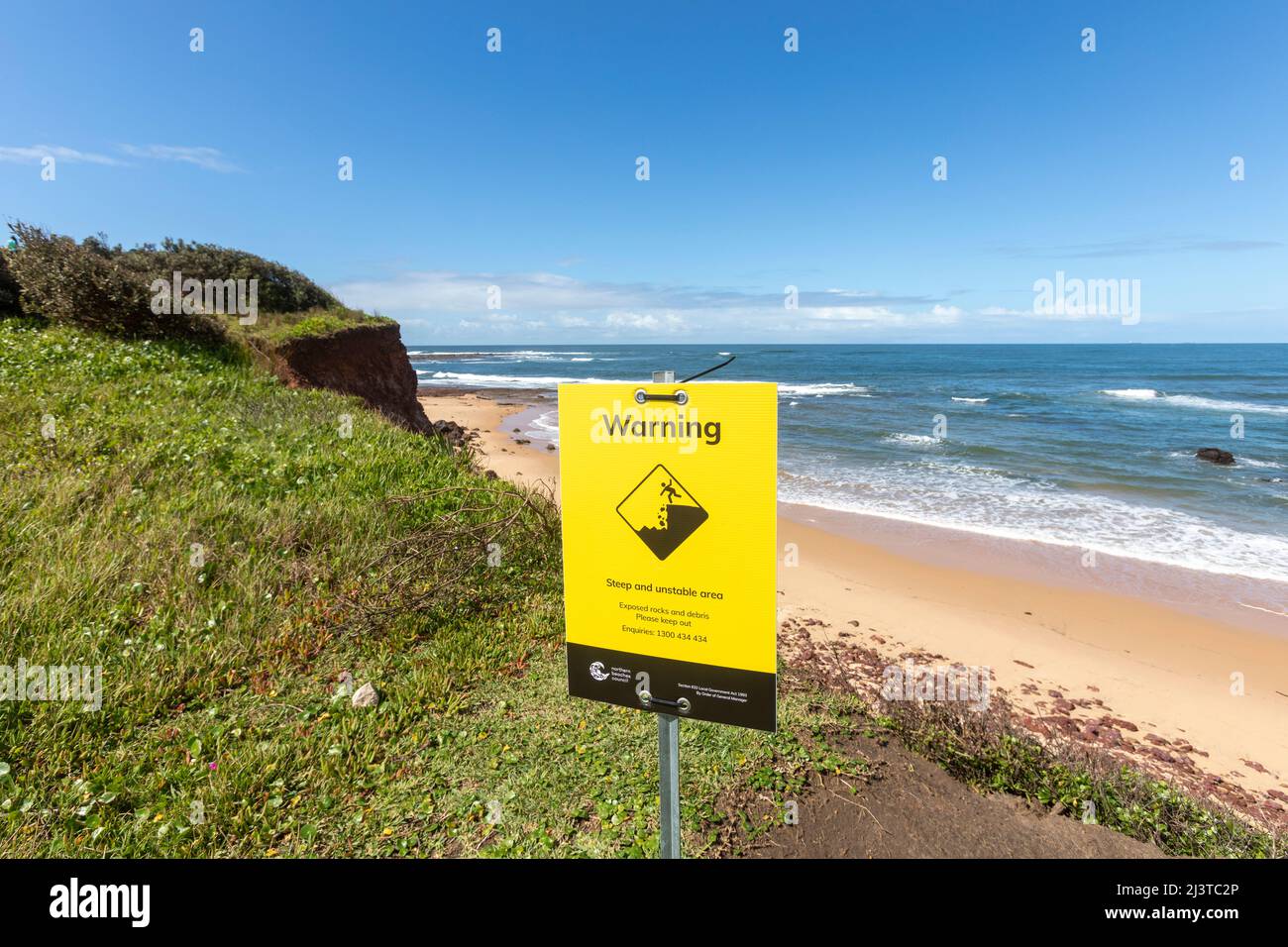 Warning sign for unstable ground and long fall at Long Reef headland with steep drop to the beach,Sydney,NSW,Australia Stock Photo