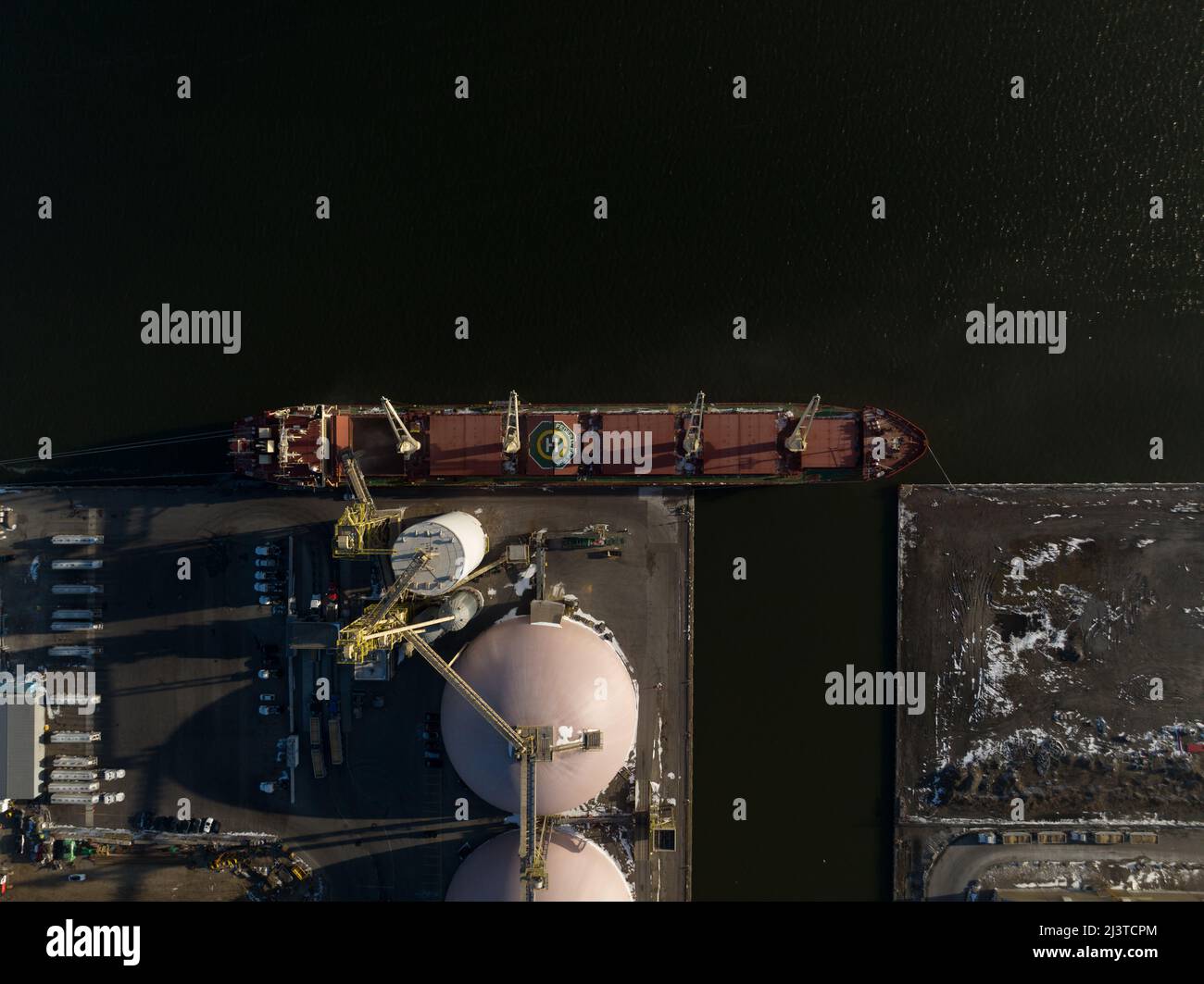 A direct overhead aerial view of a raw goods agriculture cargo ship at a dock in Hamilton, Ontario's industrial port. Stock Photo