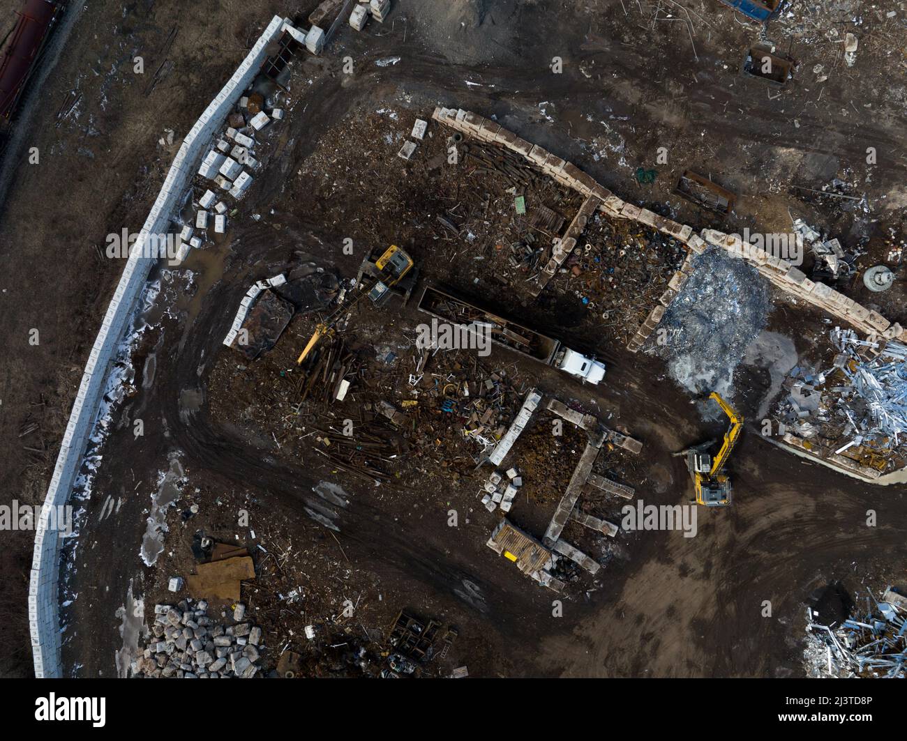 A direct overhead aerial view as a truck is being loaded by large machinery at a scrap metal recycling center for transport. Stock Photo