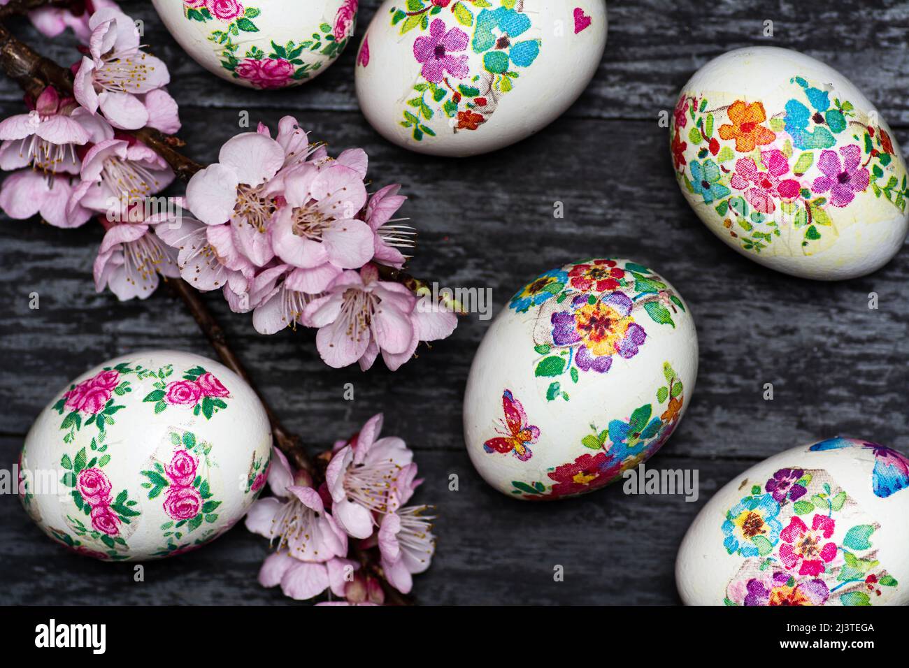 White Easter eggs made with decoupage technique with floral motifs and a flowering branch on a black rustic background. Stock Photo