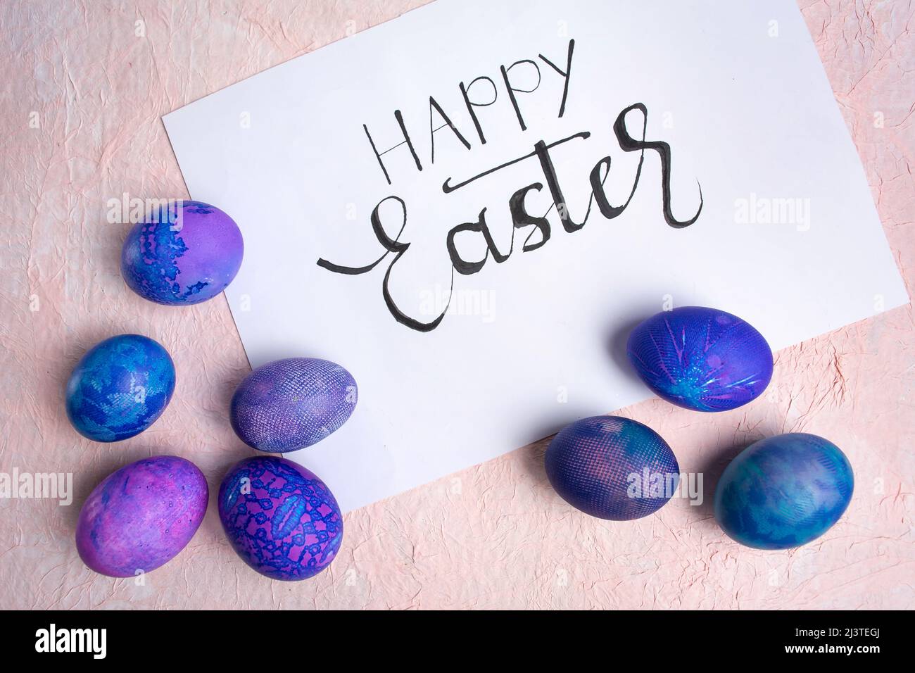 Blue purple Easter eggs with lace look and calligraphic inscription Happy Easter on a pastel background. Stock Photo