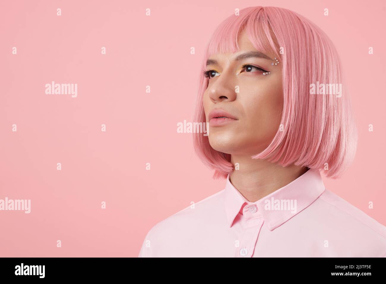 Portrait of young man with glam rhinestone makeup wearing pink bob wig Stock Photo