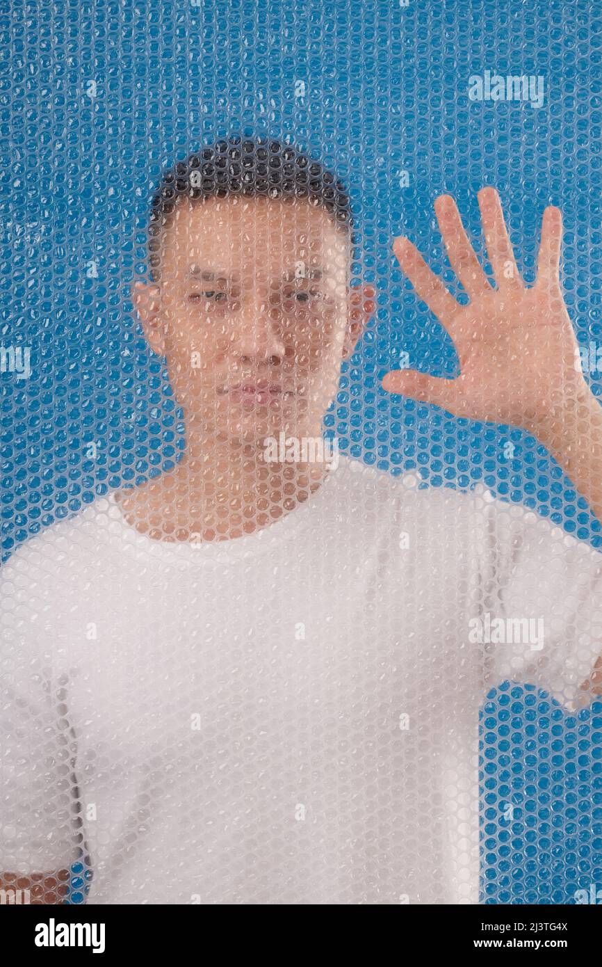 Portrait of Asian man standing behind bubble wrap and wiping with hand