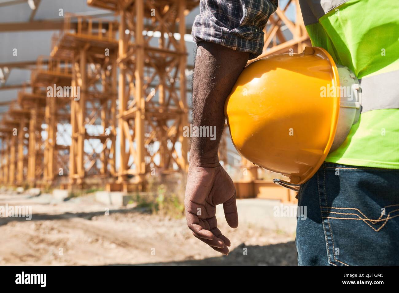 Building worker analyzing project plan and discussing blueprint while standing on construction site Stock Photo