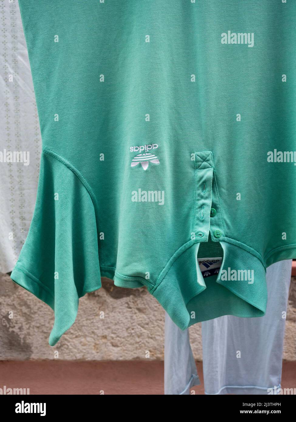 Wet Adidas polo shirt hanging outside on clothesline drying Stock Photo