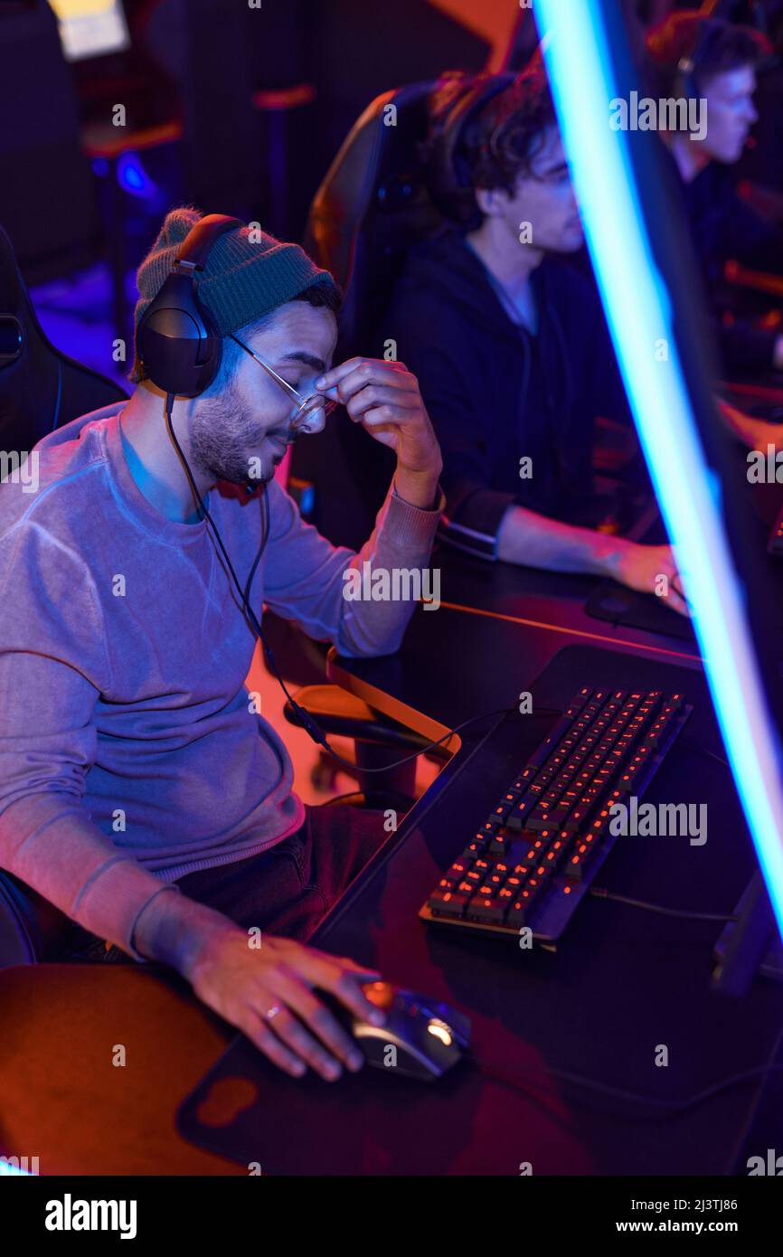 Tired mixed race esports gamer in headphones rubbing bridge of nose