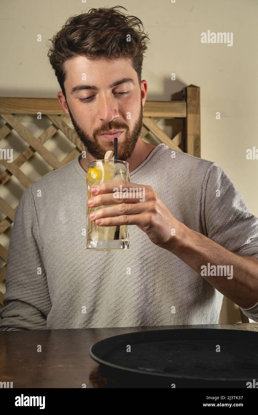 Guy having a long drink in a pub with an organic straw, young people consumption of alcohol and nightlife lifestyle concept. Stock Photo