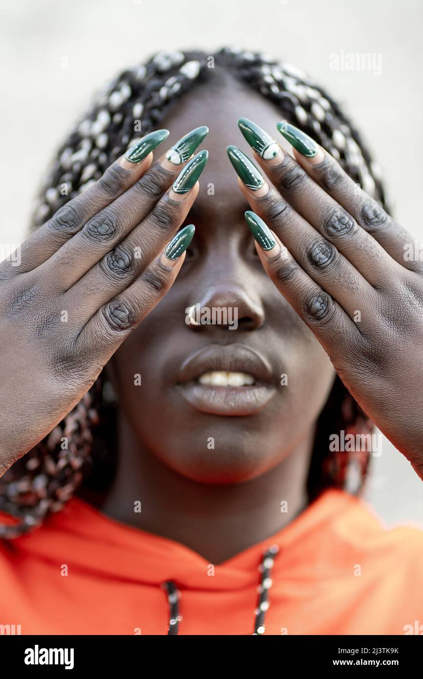 Young African woman showing nails art over her face covering eyes Stock Photo
