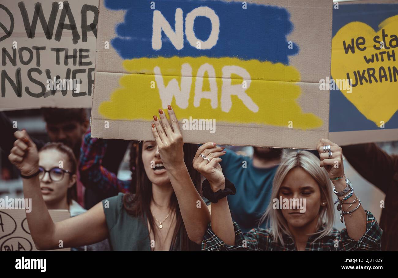 Image composition to illustrate pacifists young people protesting against the war aggression against Ukraine in 2022 from Russia. Stock Photo