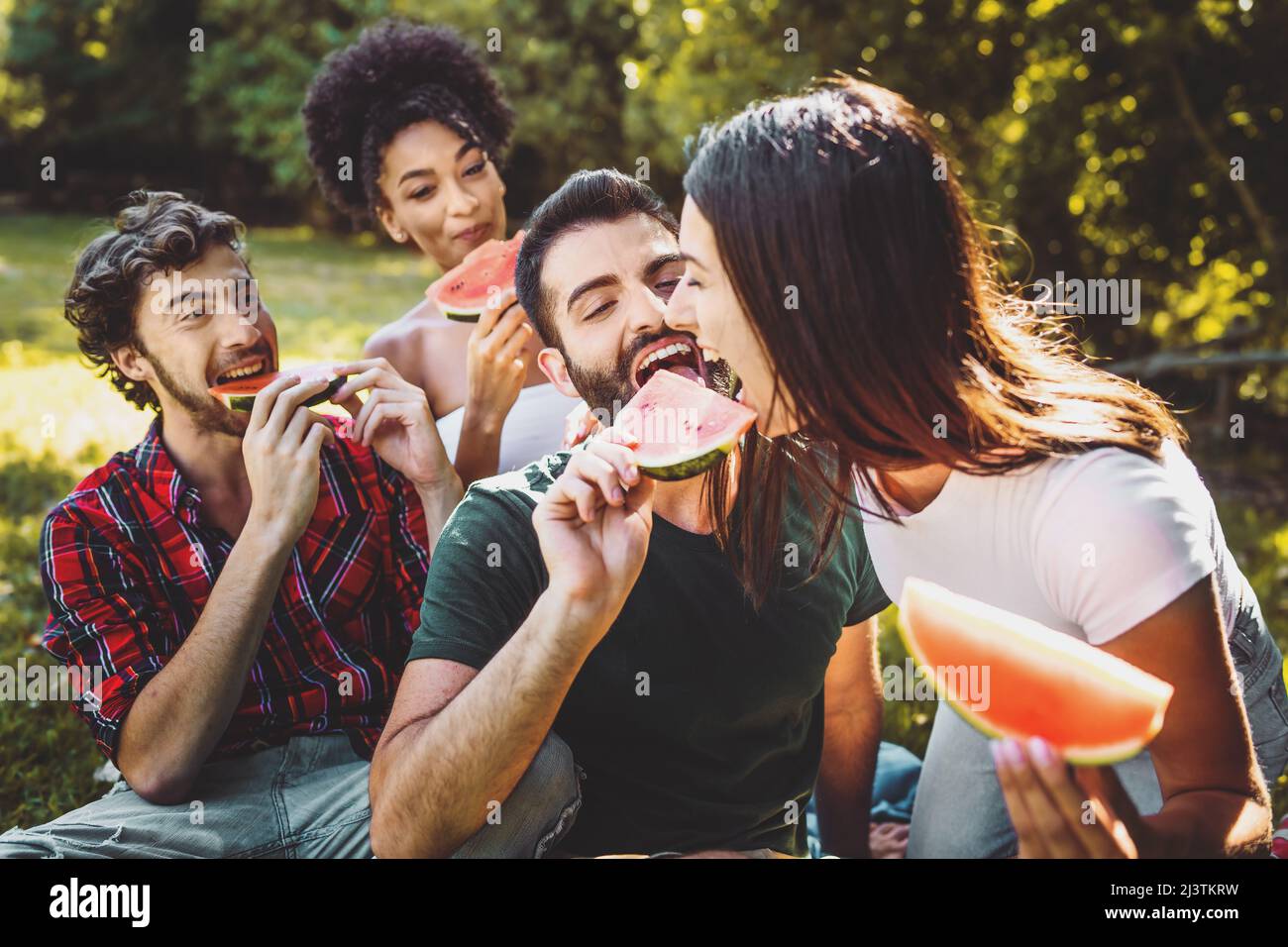 group of friends enjoying watermelon slices in the countryside having fun together on a weekend activity Stock Photo