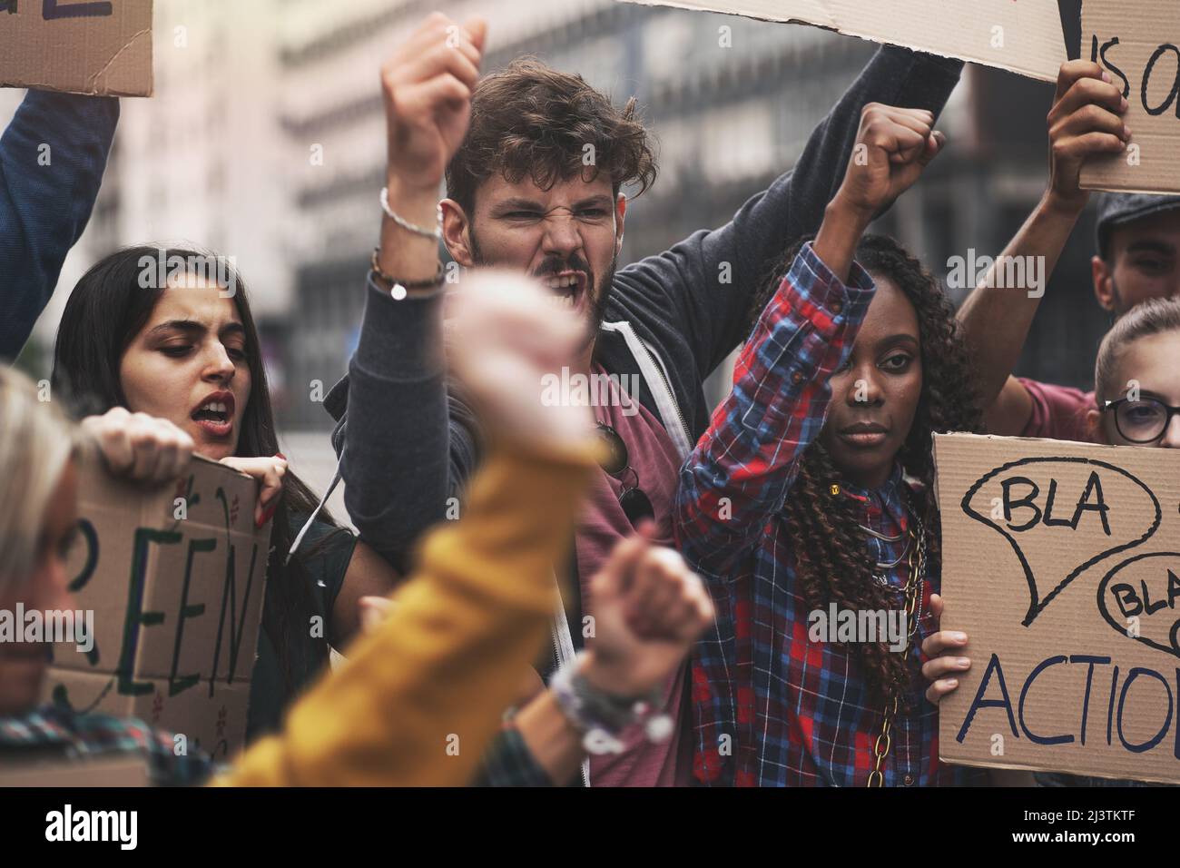 Students screaming at protest for human rights outdoors in smoke. Group of people protesting at street. Strike against politics and government. Stock Photo
