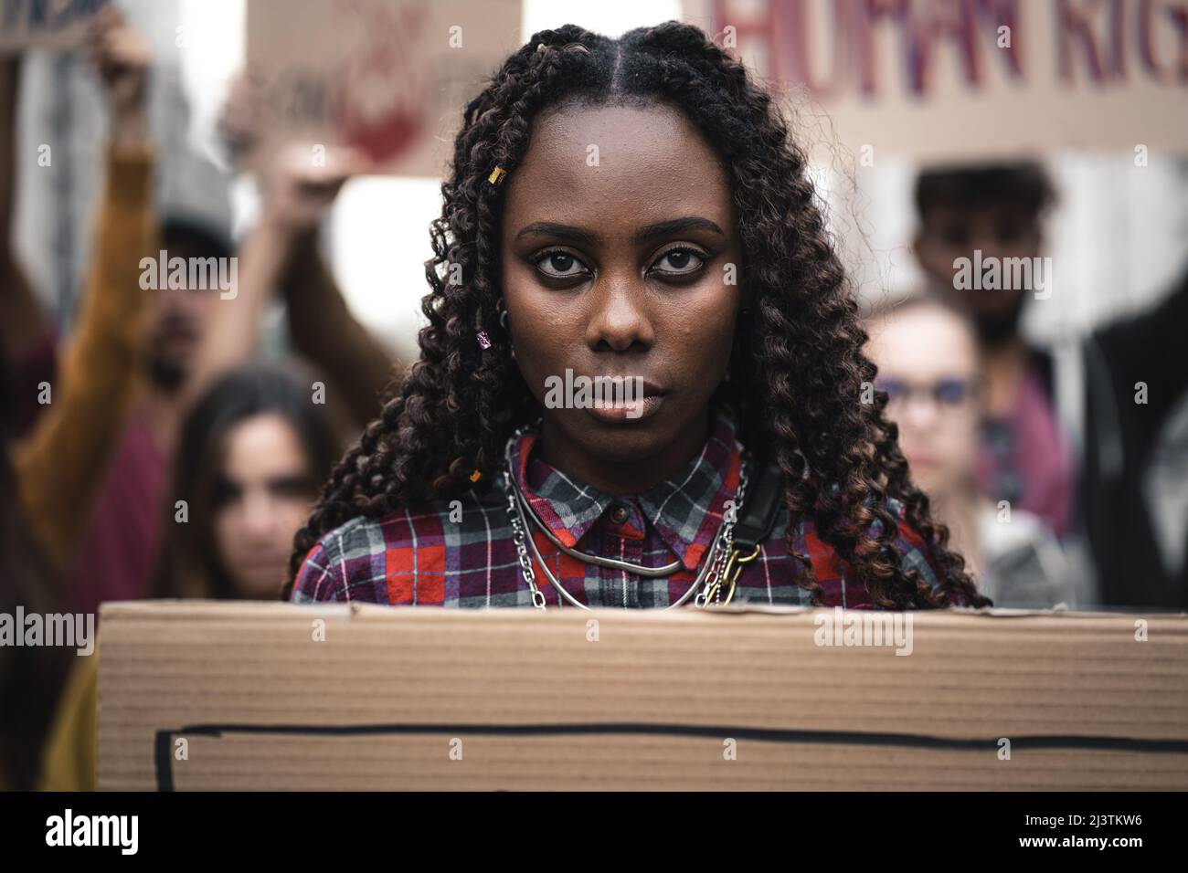 Portrait of a young African woman marching during a youth protest - face detail, other remonstrants behind - concept of young people protesting agains Stock Photo