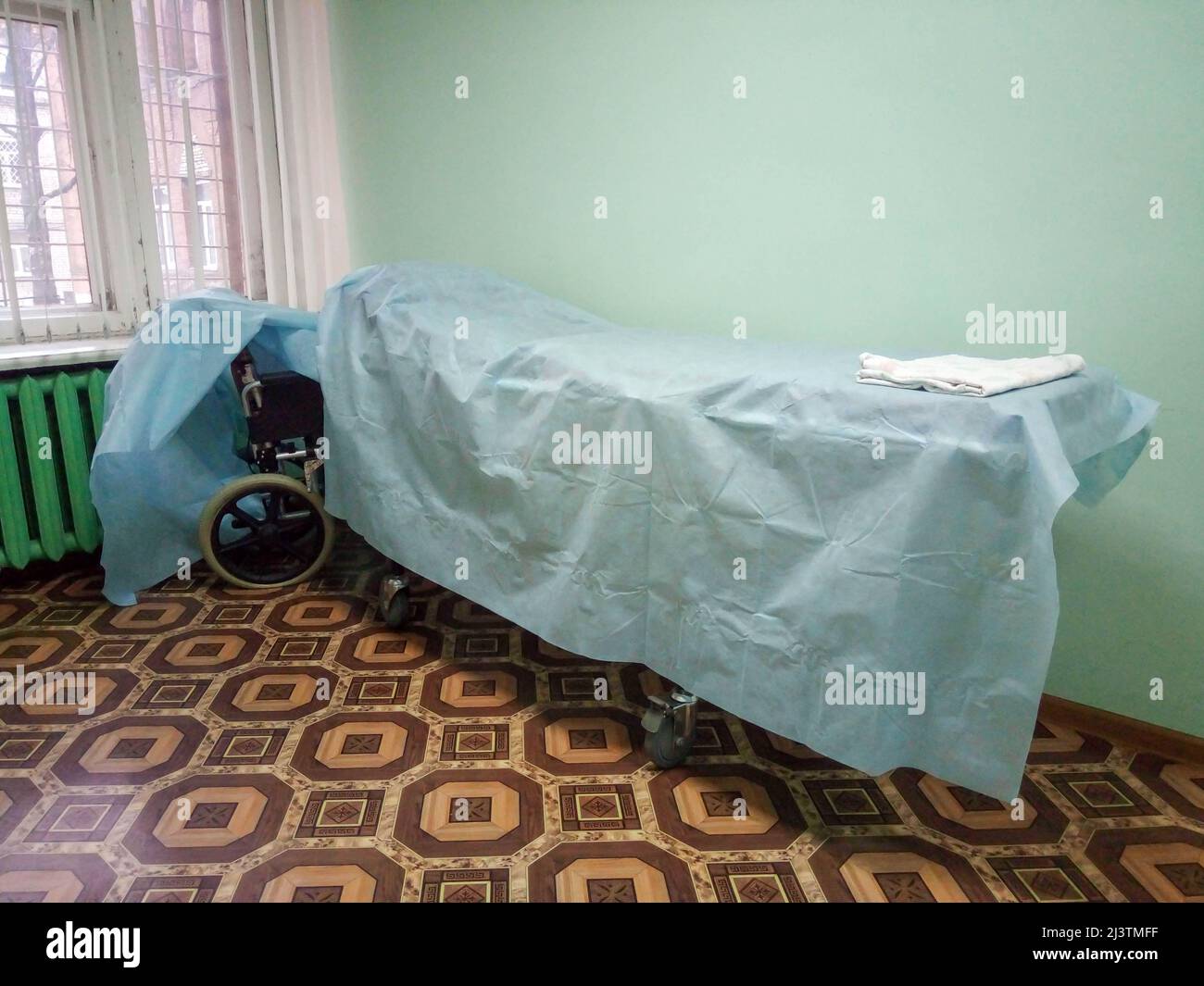 A wheelchair bed covered with a blue sheet, or a stretcher on wheels for transporting bedridden patients along the hospital corridor. Stock Photo
