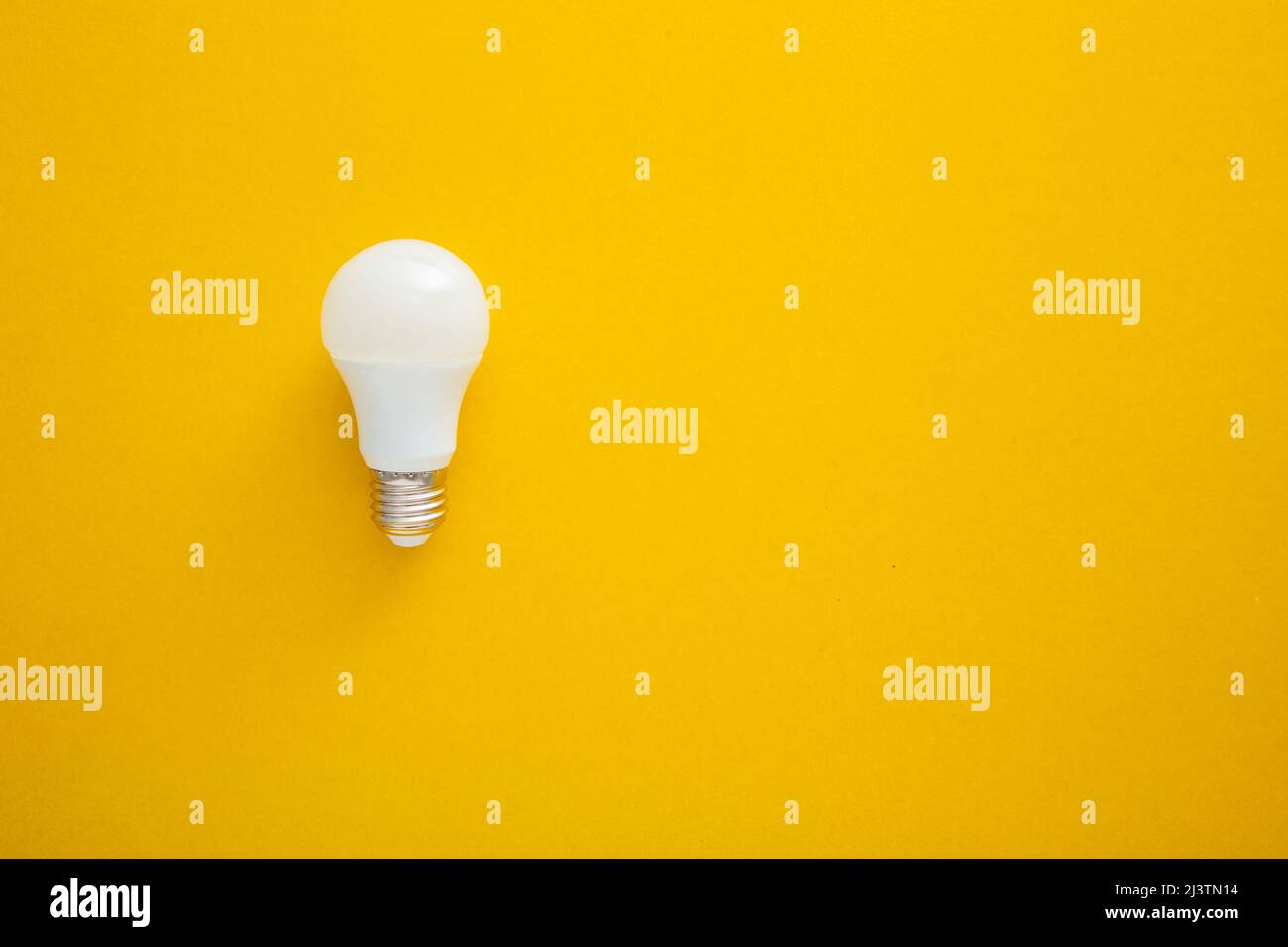White light bulb on bright yellow background in pastel colors ...