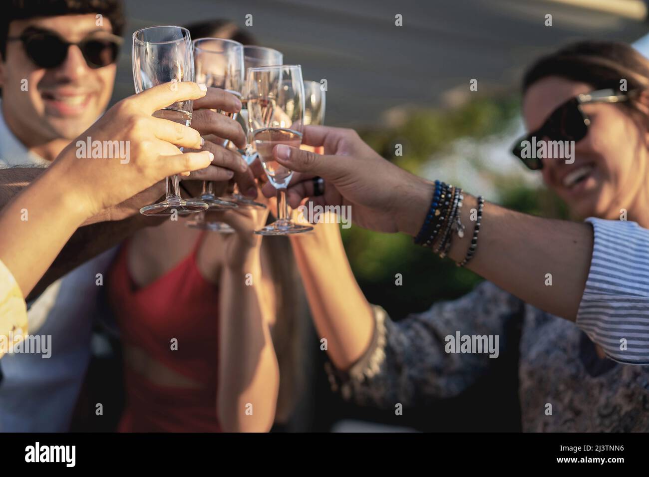 Group of happy friends drinking and toasting champagne outdoors in the terrace - Friendship concept with young people having fun together celebrating Stock Photo