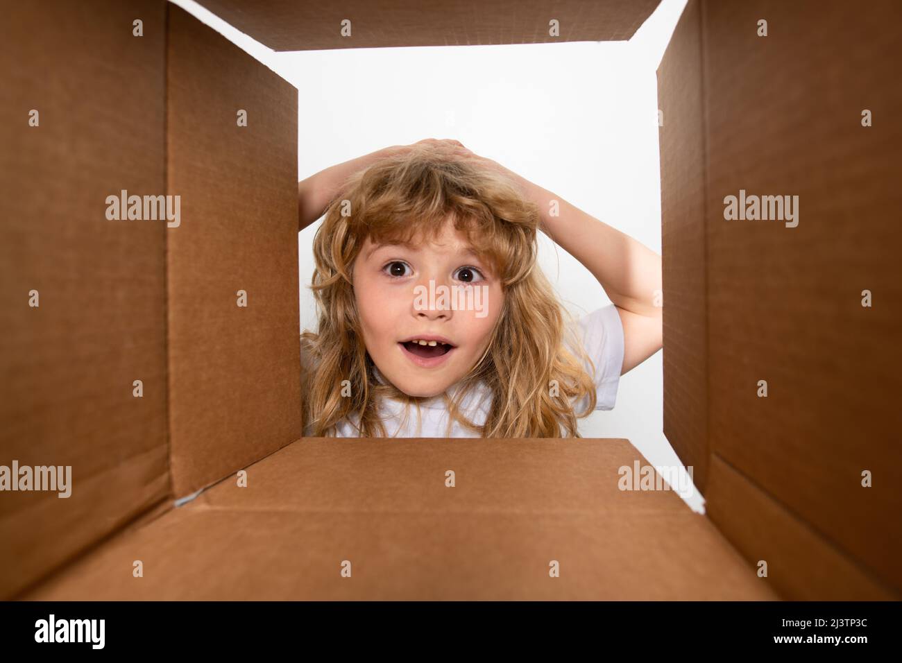 Funny surprised shocked child boy is opening gift and looking inside ...