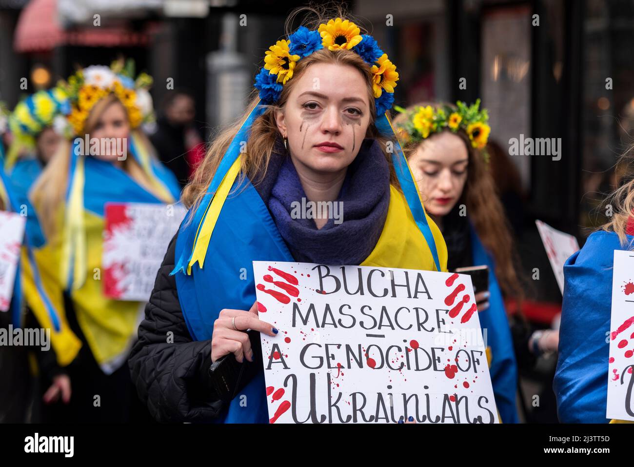 Protesters carrying out a die-in and protest, referencing the killed Ukraine civilians in towns such as Bucha during war with Russia. Bloodied sign Stock Photo
