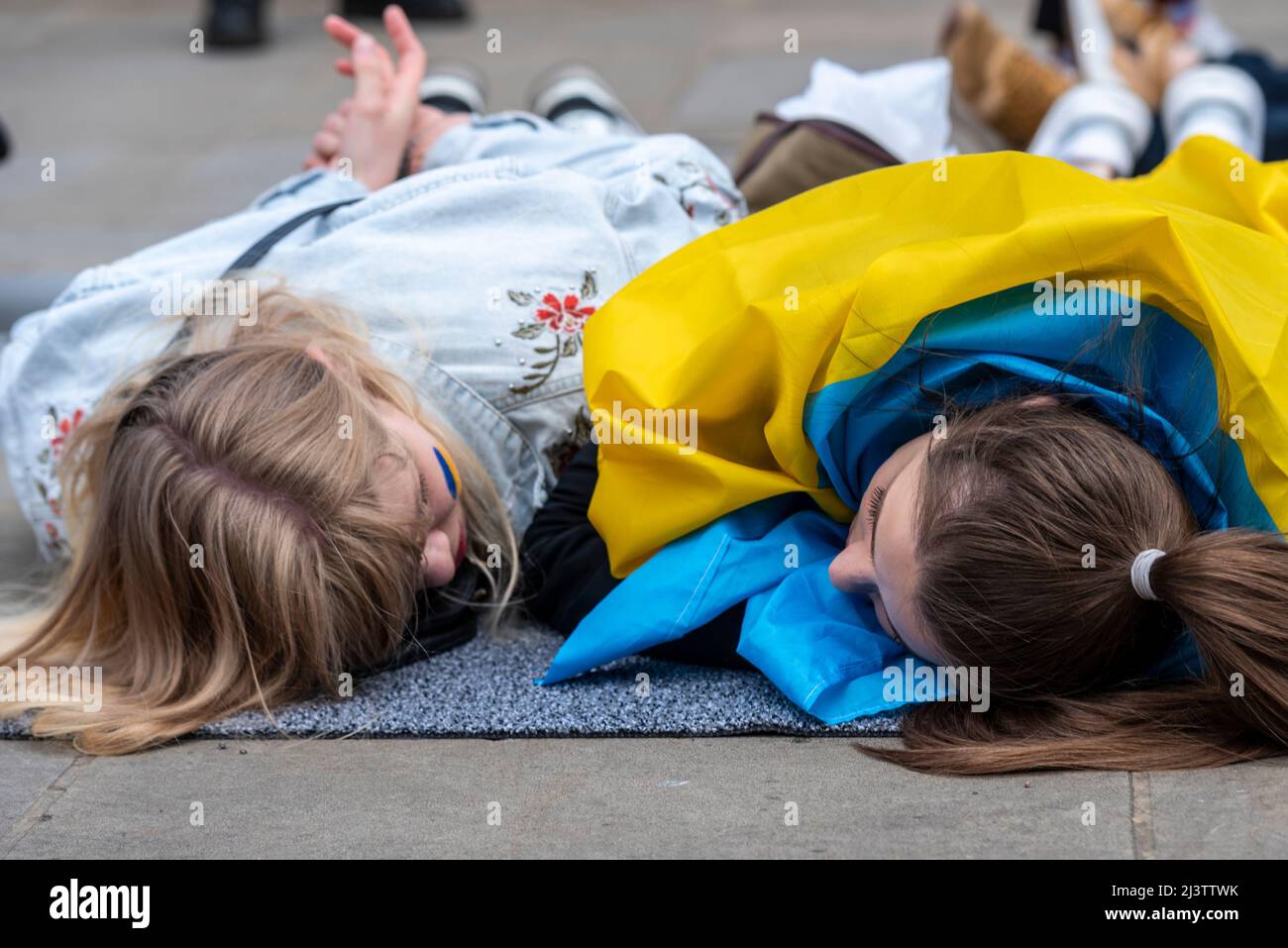 Protesters carrying out a die-in, referencing the killed Ukraine civilians in towns such as Bucha during war with Russia. Two young females 'dead' Stock Photo