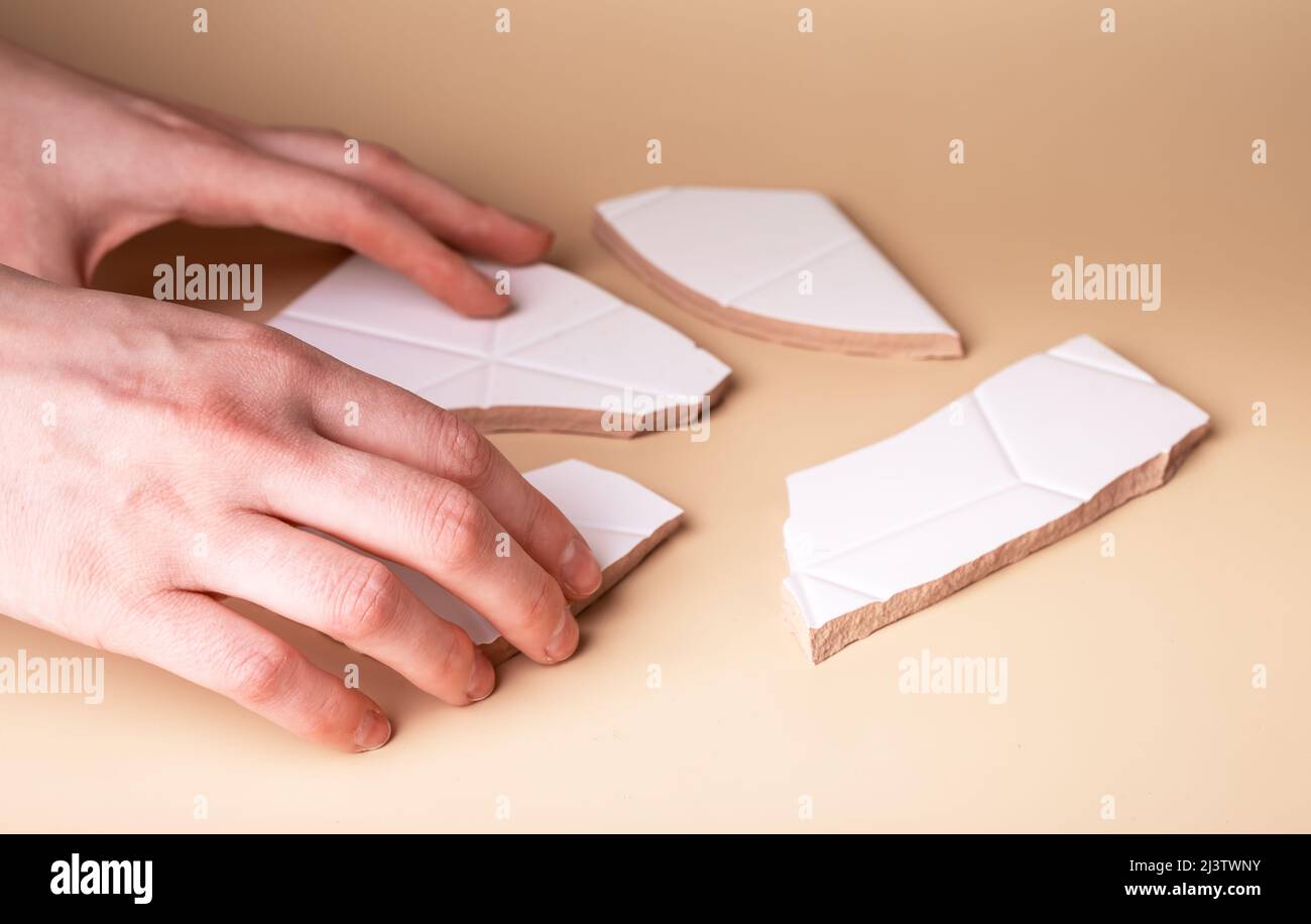 Hand taking pieces of broken tile. Touch sense and taction concept. Fingertips receptors contacting solid sharp object and receiving information about world. High quality photo Stock Photo