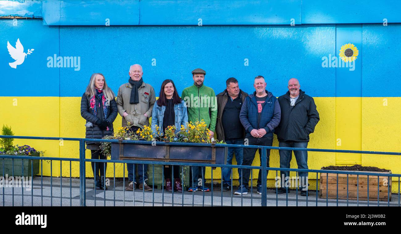 Starbeck, Harrogate, UK. 10th Apr, 2022. Members of Starbeck Community Group Jill De Witt, Andrew Hart, Lucky Hubbard, Nik Mills, John Keane, David Stead and Colin Wilson photographed in front of a 40 metres Ukrainian flag they painted over the once beautiful and now derelict Harper's building on Starbeck High Street. This is one of many projects they are working on to revitalise and motivate their local community. Credit: ernesto rogata/Alamy Live News Stock Photo