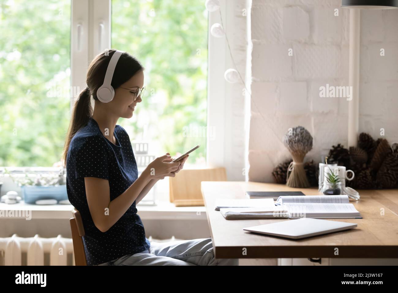 Woman in headphones holds smartphone choose music through digital services Stock Photo