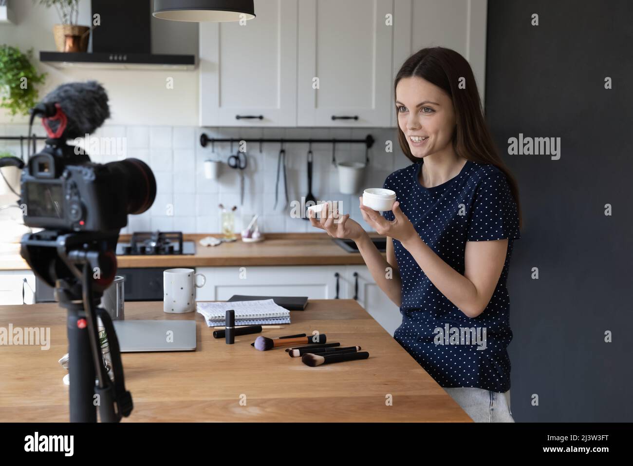 Professional beautician woman holds cream jar record vlog on camera Stock Photo