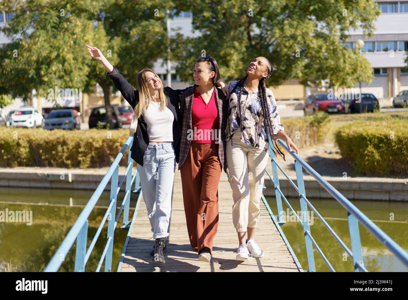 Positive diverse women walking on footbridge Stock Photo