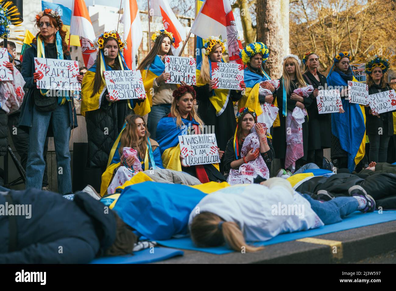 Pro-Ukrainian women at a demonstration in London against the war in Russia. Surrounded by Ukrainian flags. Banners against Bucha massacre. Lying Stock Photo