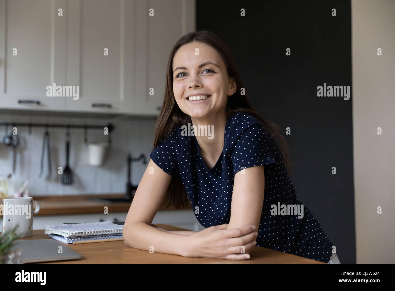 Woman standing in kitchen leaned at table staring at camera Stock Photo