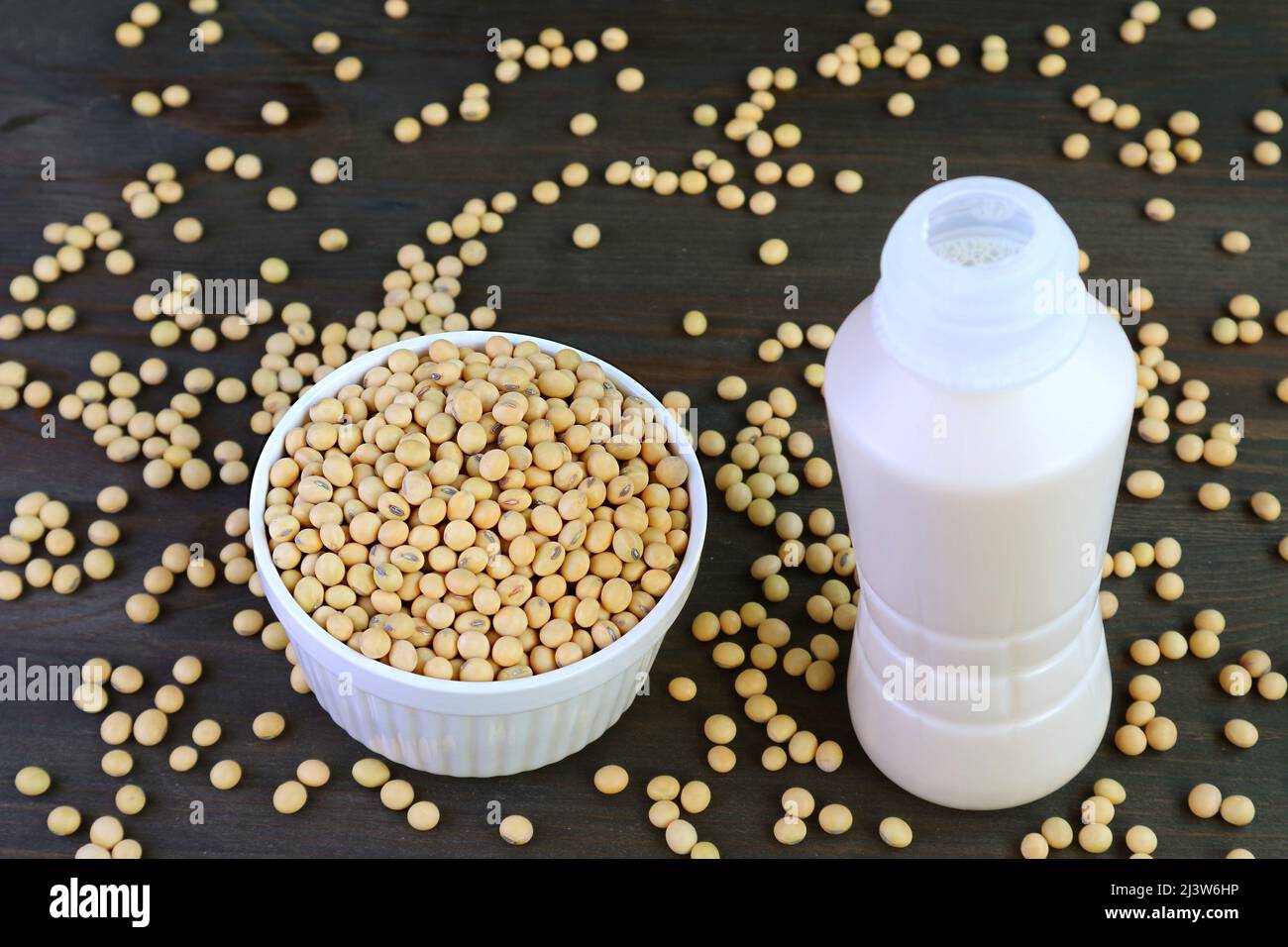 Bottle of Soy Milk Isolated on Black Wooden Table with Scattered Soy Beans Stock Photo