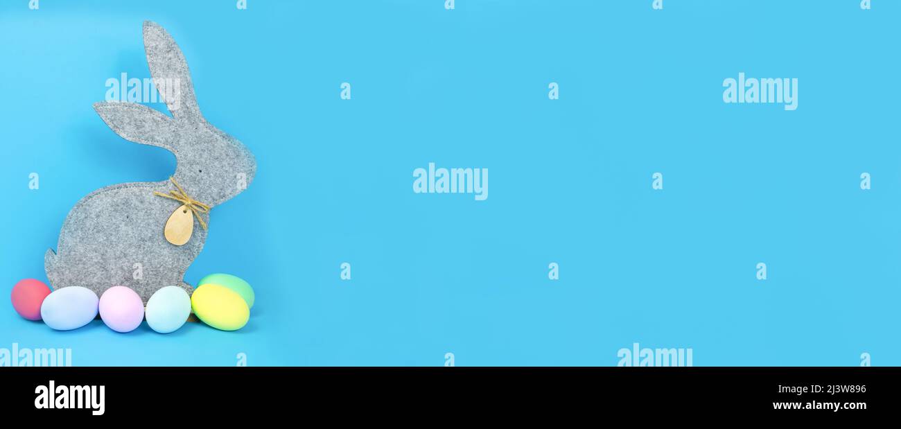 Easter, soft, gray hare and eggs are plain, multi-colored on a blue background.  Stock Photo