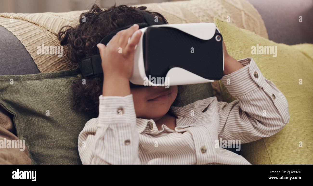 Glued to the screen. Shot of a little boy watching movies together through virtual reality headsets at home. Stock Photo