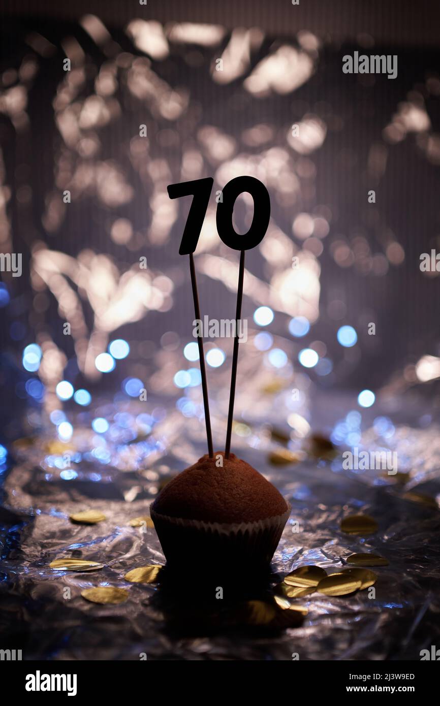 Homemade anniversary cupcake with number 70 seventy and blurred bright background. Minimalistic birthday or anniversary gift card concept. High quality vertical image Stock Photo