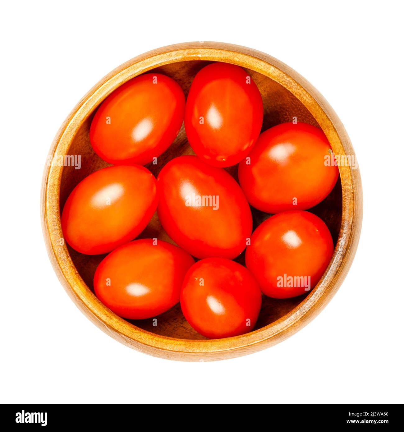 Red grape tomatoes, in a wooden bowl. Ripe, small, oblong cocktail tomatoes in the size of a thumb tip, shaped like a plum tomato, with sweet taste. Stock Photo