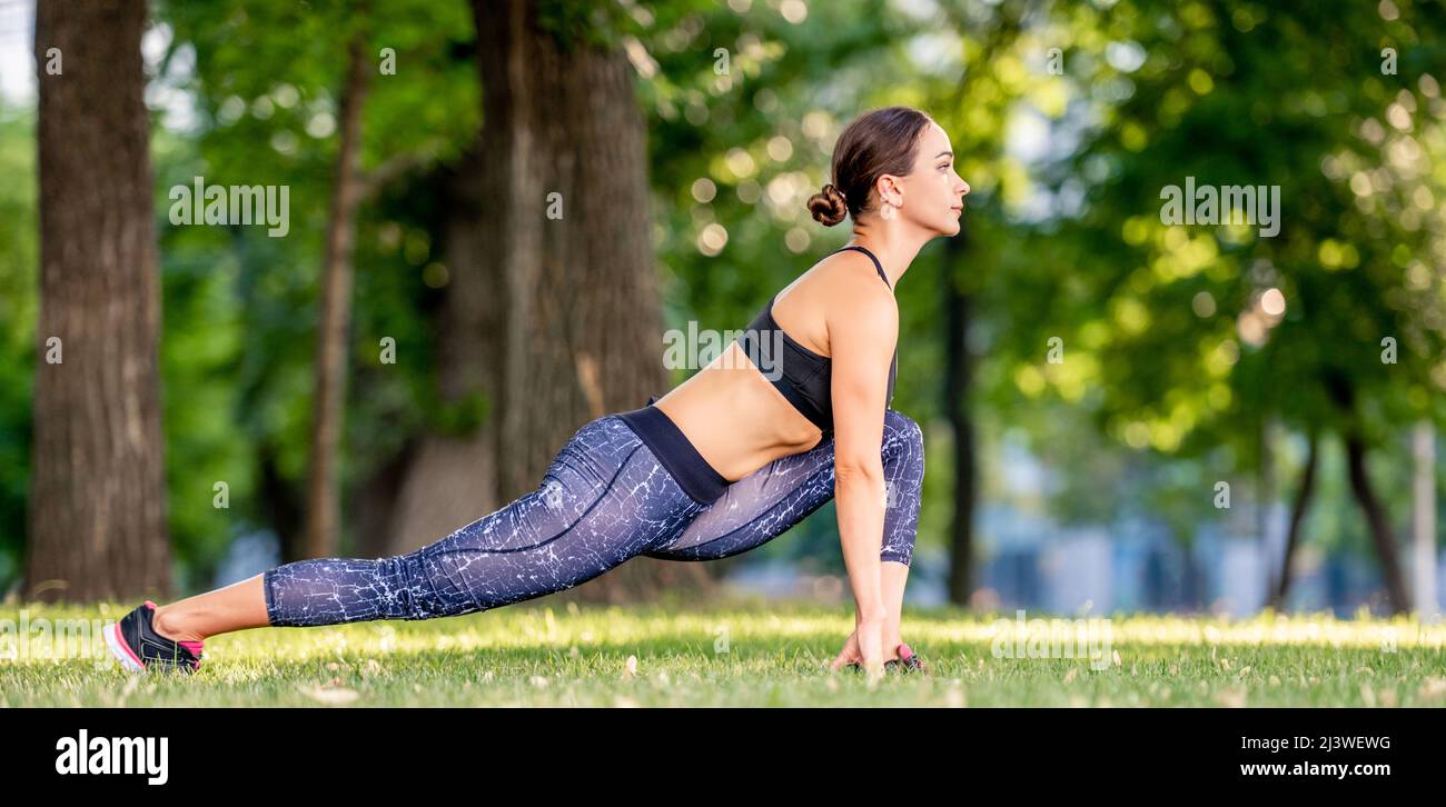 Yoga teacher doing Horizon Lunge pose in park - a Royalty Free