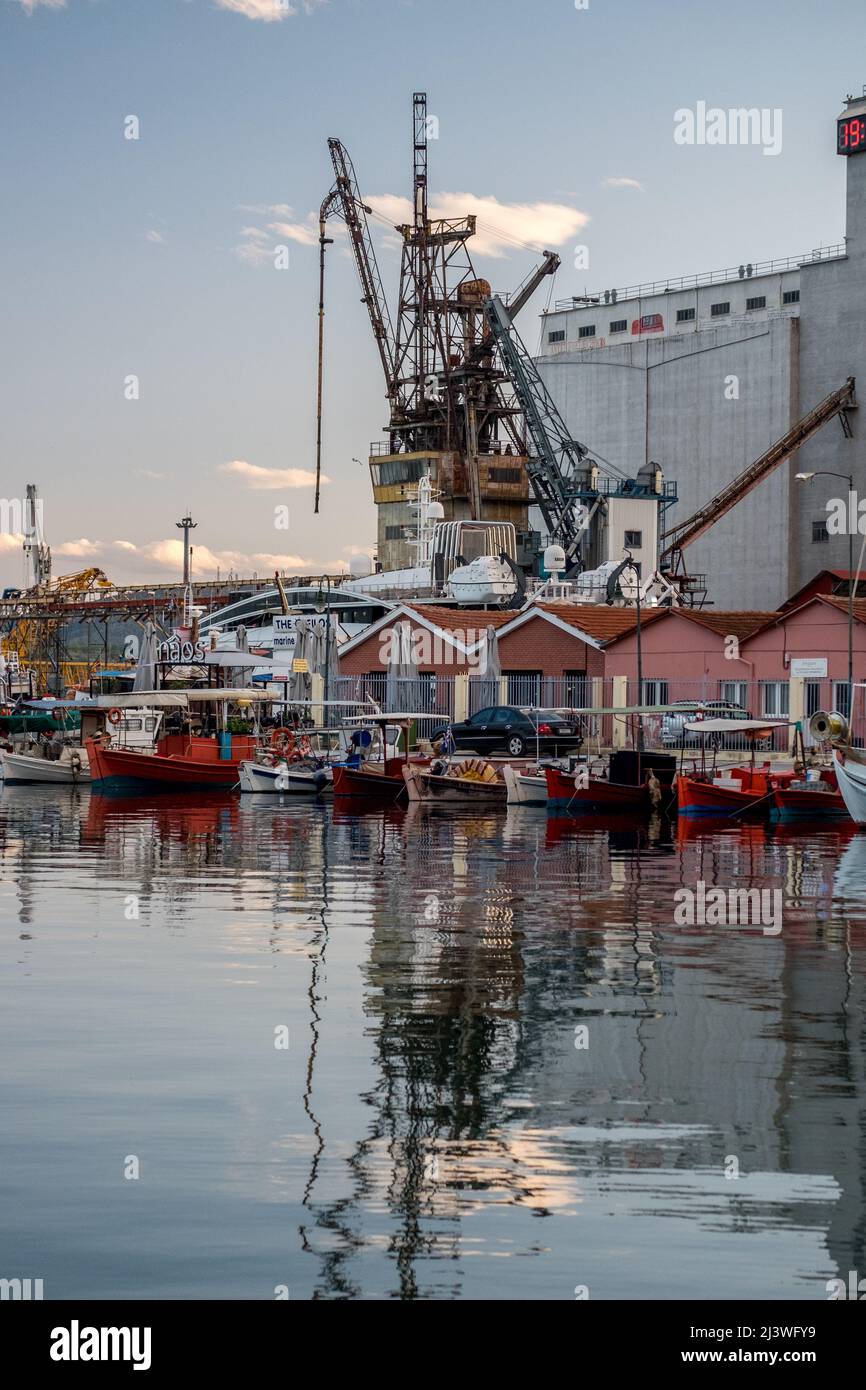 Seascape scenery with fishing boats and big port cranes on the harbor of Volos, Greece Stock Photo