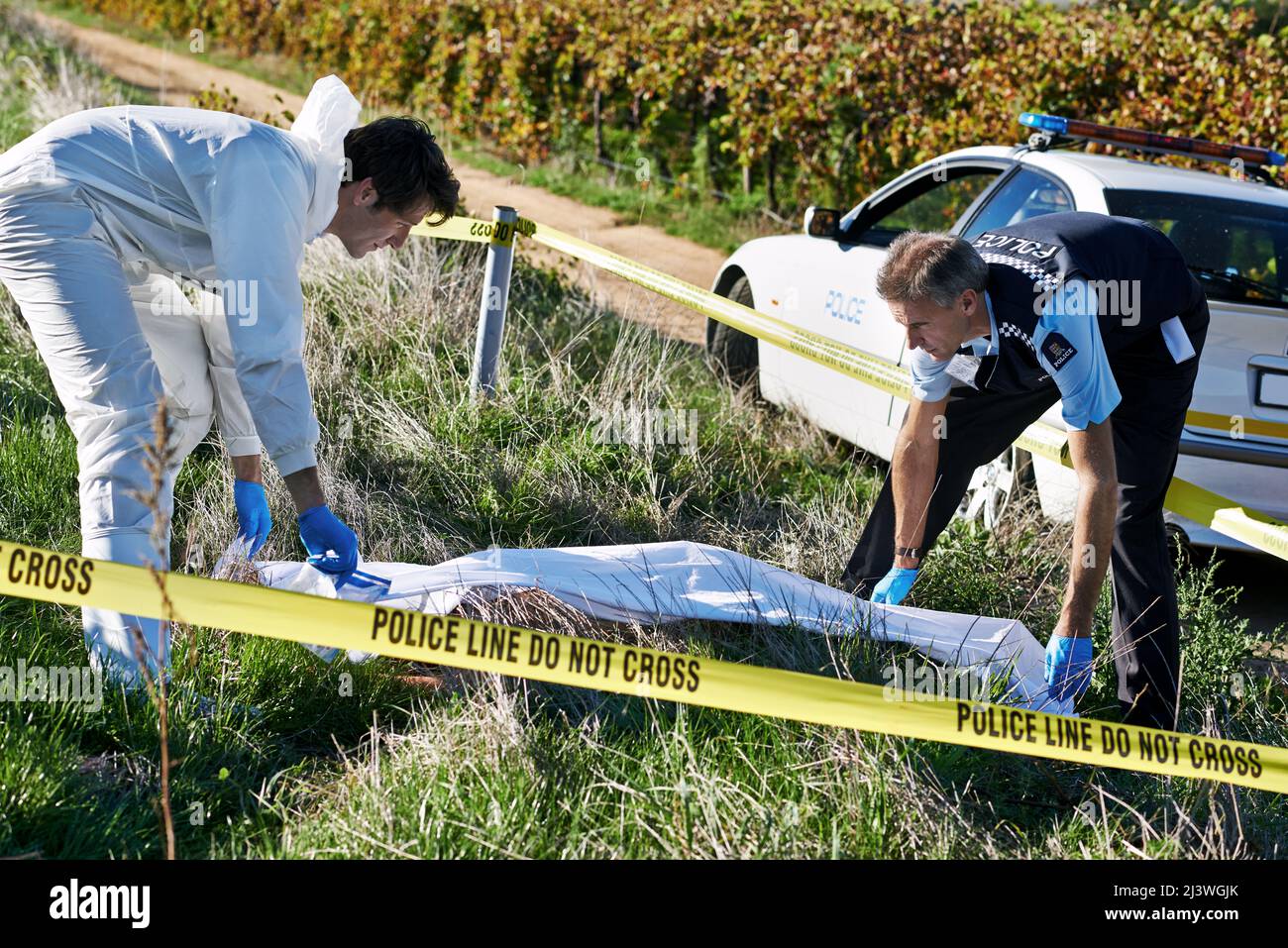 Covering the body. Shot of two investigators picking up a body bag at a crime scene. Stock Photo