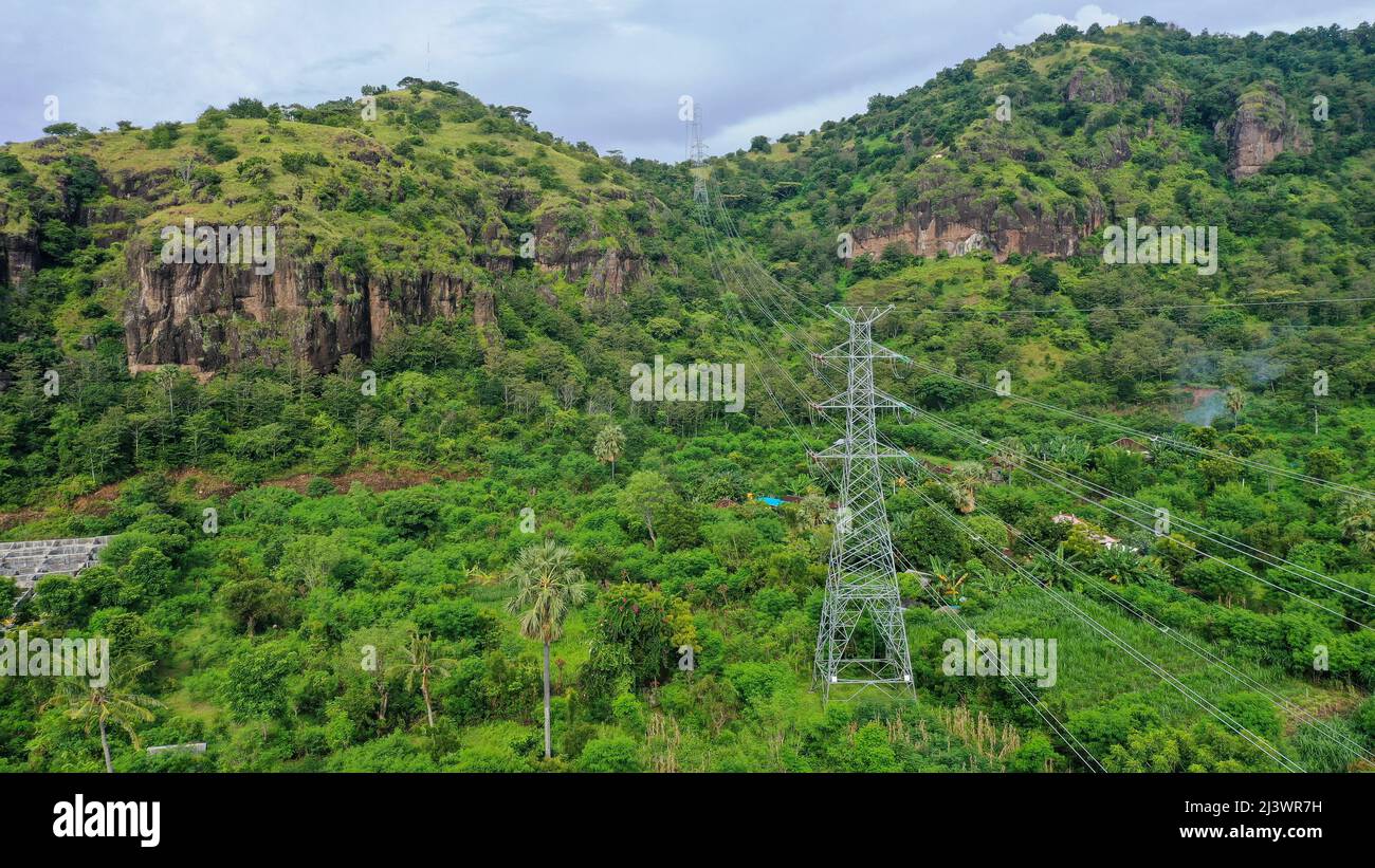 Power Towers Transmit Electricity To City Above Mountain Forest Stock