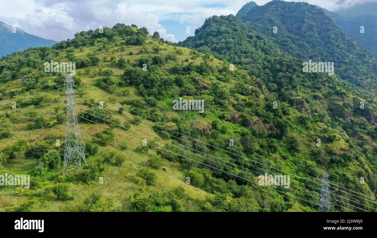 Power Towers Transmit Electricity To City Above Mountain Forest Stock