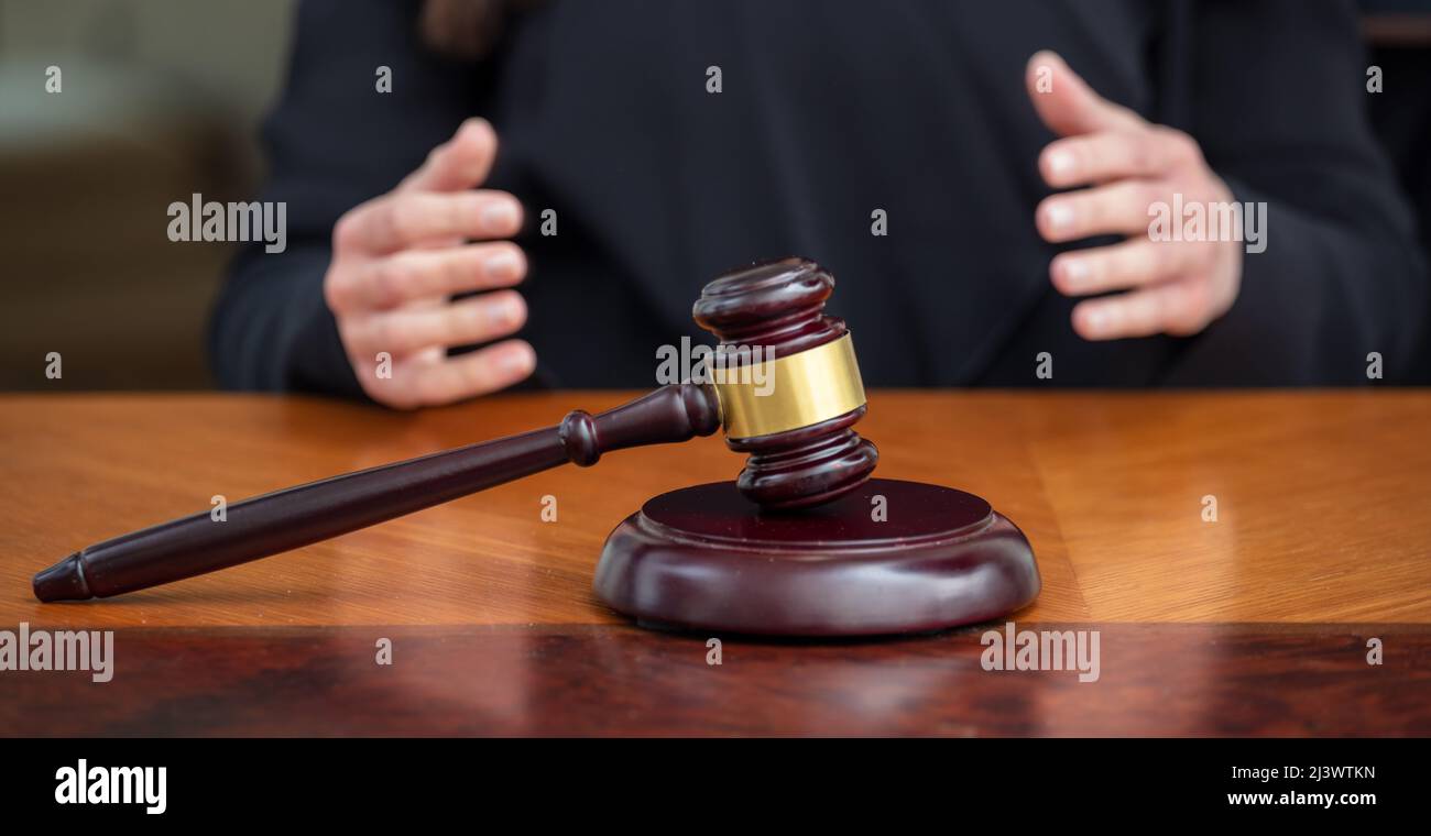 Judge gavel on wooden law court bench, blur female hands, close up view. Justice and punishment concept Stock Photo
